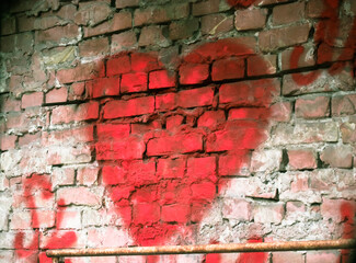 A big red heart painted on a red brick wall. Rough background with a symbol of love. Valentine's Day declaration of love on February 14. 