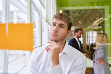 Business man thoughtfully looks at sticky notes