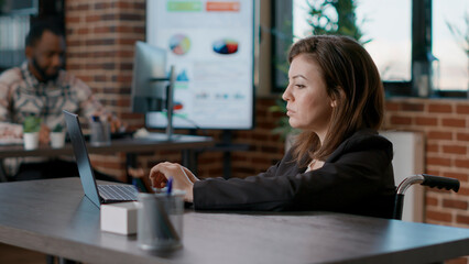 Portrait of businesswoman analyzing financial charts on laptop, working on project strategy to create statistics data. Female worker with disability using graphs on computer to plan growth.