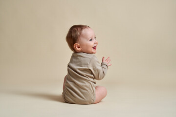 Happy caucasian baby sitting on nude background
