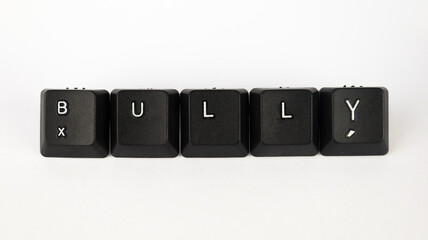 Bully text created with keyboard keys isolated on white background, white bully letters on black keyboard, top view