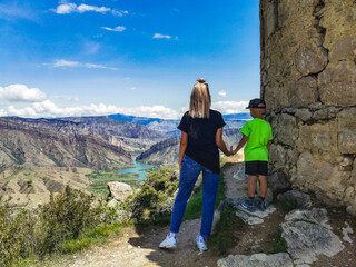 A girl with a child against the background of mountains and the fortress of Gunib. Russia, Dagestan. June 2021.