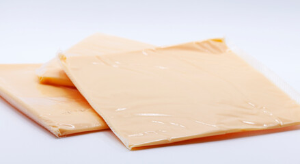 sliced pieces of cheese in plastic on white background