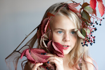 Naklejka premium Portrait of little girl with red ivy leaves on head
