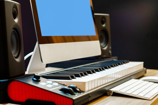 midi piano, desktop computer and loudspeakers monitor on desk. music production and online music e-learning concept