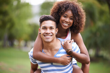 The cute young couple in the park. Cropped portrait of a young man giving his girlfriend a piggyback ride at the park.
