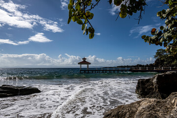 a pier in the sea and a gazebo in a landscape against the background of the sea and blue sky 