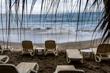 white deckchairs on the sandy beach against the backdrop of the sea 