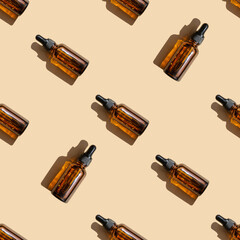 Seamless pattern of mock-ups of amber-colored glass bottles with dropper lids on beige background. Unmarked package from facial serum with a hard shadow cast, located randomly