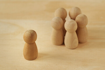 Wooden pawns representing group of people in circle and person alone - Concept of racism, social...