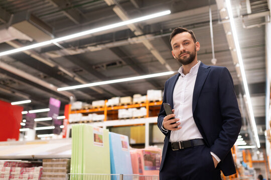 presentable owner of a hardware store in a business suit looks at the camera on the background of a hypermarket