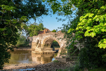 Leaves framed view to medieval Aylesford bridge and river in Kent, England