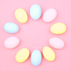 Creative Easter layout made of colorful eggs and flowers on a pink background. Circle wreath of easter eggs flat concept.