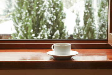 Cup of tea stands on wooden windowsill