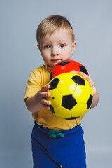 Little european boy, fan or player in yellow and blue uniform with a soccer ball, supports the soccer team on a white background. Football sport game, lifestyle concept. Isolated on white background