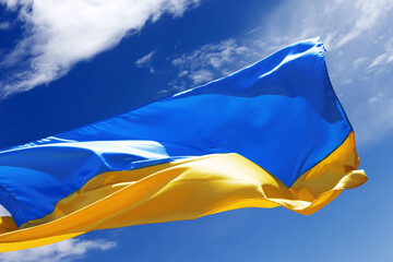Sunlight flag of Ukraine waving on a peaceful blue sky