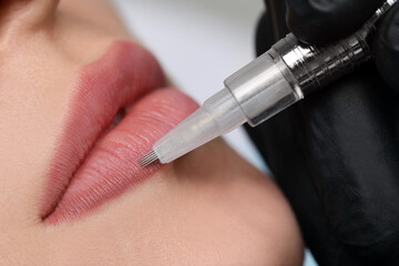 Young woman during procedure of permanent lip makeup in beauty salon, closeup