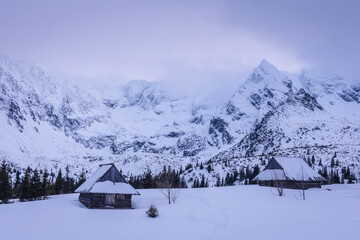 Fototapeta na wymiar Mountain chalet in the Tatras during the blue hour. Winter mountain landscape with a view of the mountain ridges.
