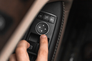 Close-up hand pressing button automatic power controlling window in car. Modern luxury car interior with leather background photo