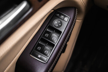 Obraz na płótnie Canvas Car door and windows open close buttons. Luxury car interior with brown leather background