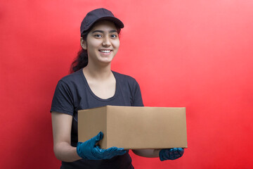 Young Delivery Woman Holding Cardboard Box Against Color Background