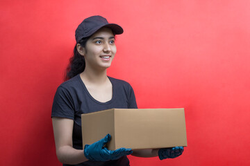 Young Delivery Woman Holding Cardboard Box Against Color Background