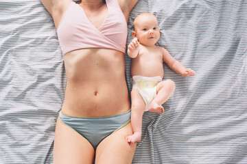 The postpartum (or postnatal) period. Young mother with visible postpartum body marks and her cute...