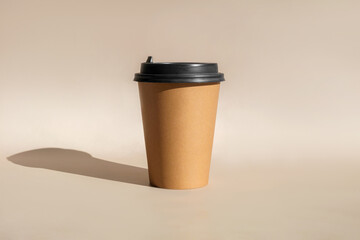 One Brown coffee paper cup. Mock-up with lid. Set of craft paper cups for coffee or tea on beige background. Front View. Zero waste, plastic free concept. Disposable Recycled cups