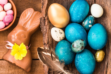 Easter eggs, chocolate bunny and sweets on wooden background.	