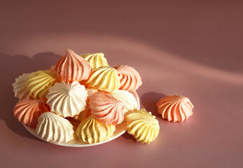 meringue pink, white, yellow on a saucer on a pink background