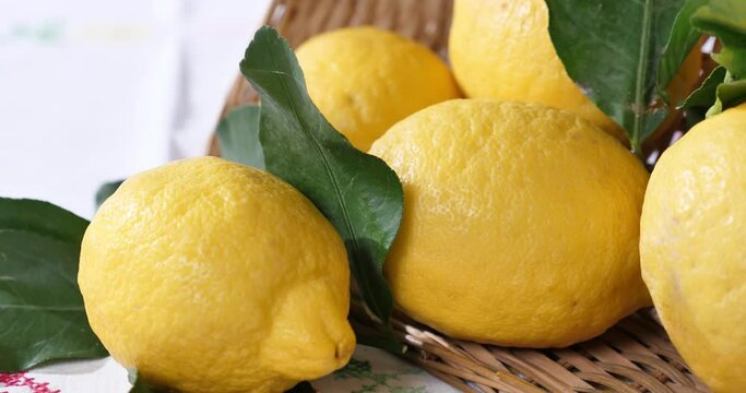 Limoni con foglie e cestino sulla tavola con tovaglia ricamata