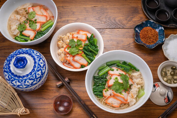 Red Pork Wonton Noodles in hot soup and vegetable. Wonton Noodles in white bowl on wooden background.
