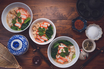 Red Pork Wonton Noodles in hot soup and vegetable. Wonton Noodles in white bowl on wooden background.
