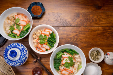 Red Pork Wonton Noodles in hot soup and vegetable. Wonton Noodles in white bowl on wooden background.