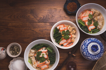 Red Pork Wonton Noodles in hot soup and vegetable. Wonton Noodles in white bowl on wooden background.