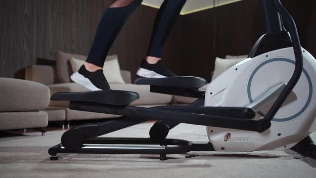 close up female legs running on elliptical orbitrek machine in fitness gym