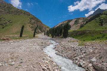 Beautiful mountain river valley with cloudy sky background. Barskoon river valley. Beautiful summer landscape. Scenic background.