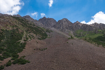 Rockslide in the mountains. Scenic background. Natural summer landscape. Beautiful mountains with landslide. Barskoon river valley.