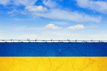 Muro con i colori della bandiera ucraina recintato da filo spinato.