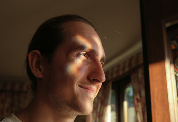 Smiling man with light spectrum on face.
