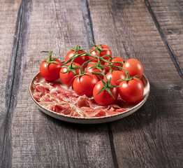 Plate with prosciutto parma and tomatoes, rustic table, italian breakfast, stock photo