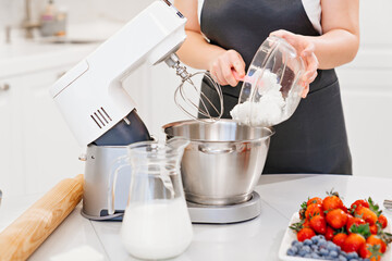 women cook adds a cottage cheese cream to prepare dough or cream in a mixer bowl