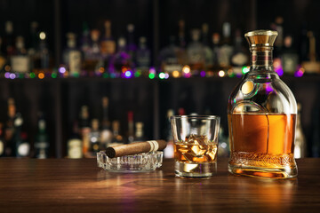 close up view of cigar, bottle of rum and a glass aside on color back. 