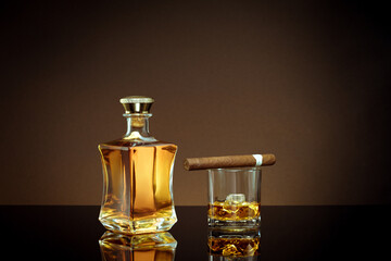 close up view of cigar, bottle of whiskey and  glass aside on color back. 