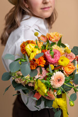 people and floral design concept - close up of pensive woman with bunch of flowers over beige background