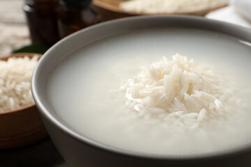 Bowl with rice soaked in water on table, closeup