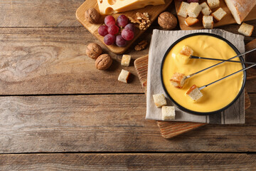 Tasty cheese fondue and snacks on wooden table, flat lay. Space for text