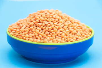 Red lentils pile or masoor dhal isolated on blue background,