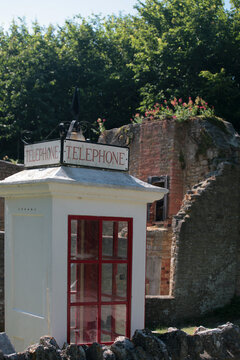 An old-fashioned WW2 telephone kiosk and ruined house in the abandoned village of Tyneham, Isle of Purbeck, Dorset, England