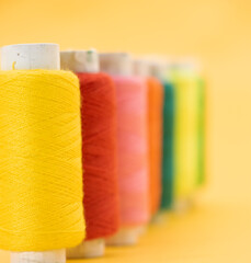 different color yarn or spool thread over on yellow background,red,yellow,blue,black color yarn